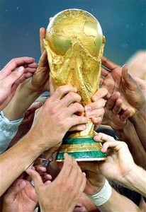 As mãos dos jogadores brasileiros seguram o Troféu da Copa do Mundo FIFA ao conquistar o penta em 2002