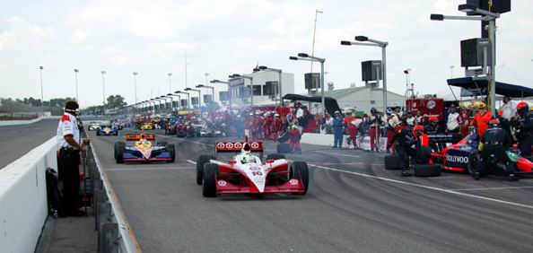 Scott Dixon sai dos pits.  esquerda dele, a equipe Mo Numm reabastece o carro de Alex Barron - foto de 10.08.2003.